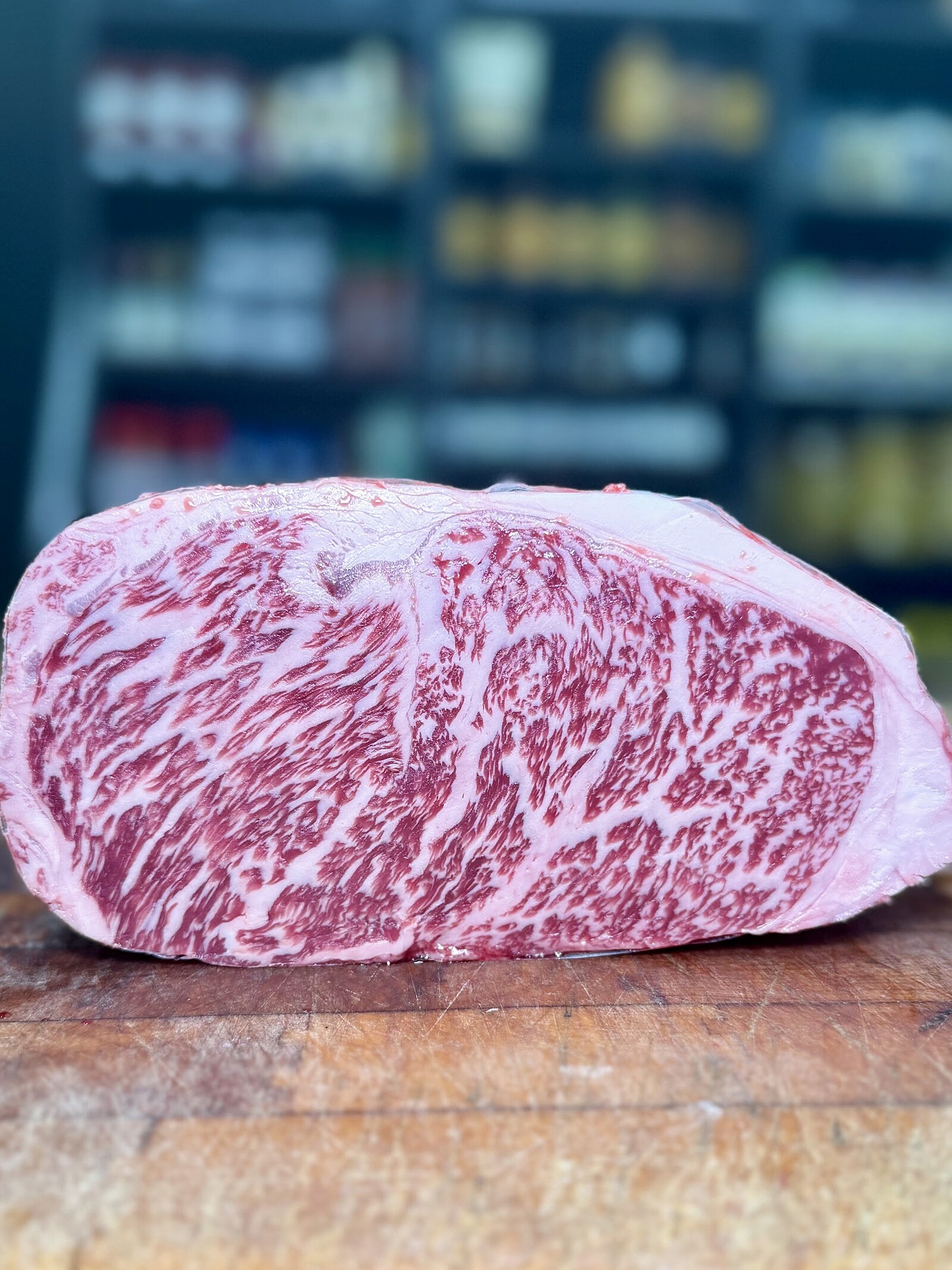 An intensely marbled Australian Wagyu striploin on the butcher block