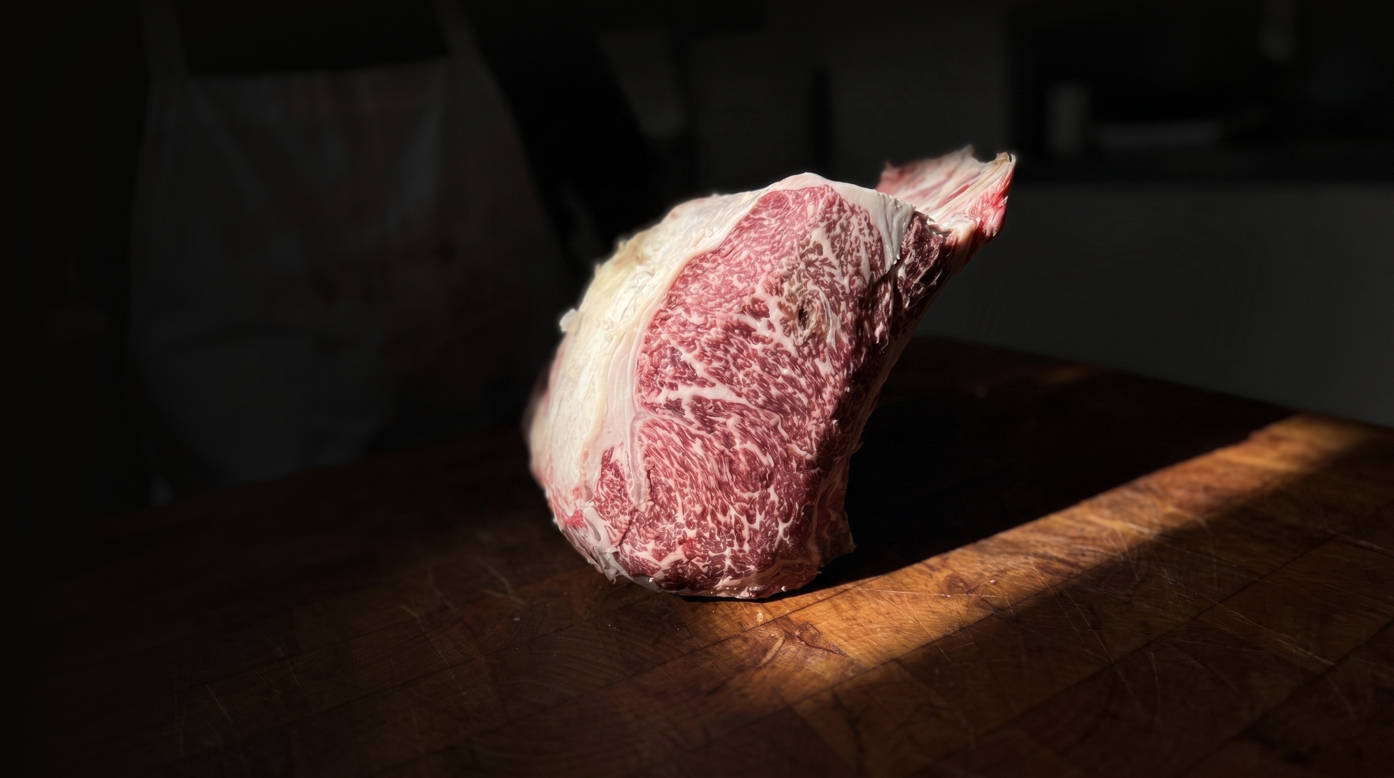 A bone-in marbled ribeye on the butcher block